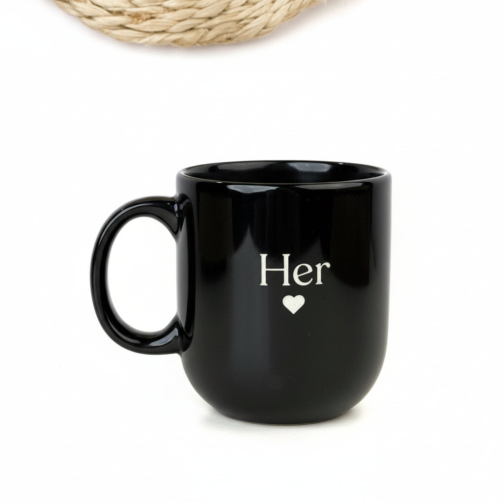 Two black mugs stacked on top of each other, one with 'His' and the other with 'Her', on a white background.