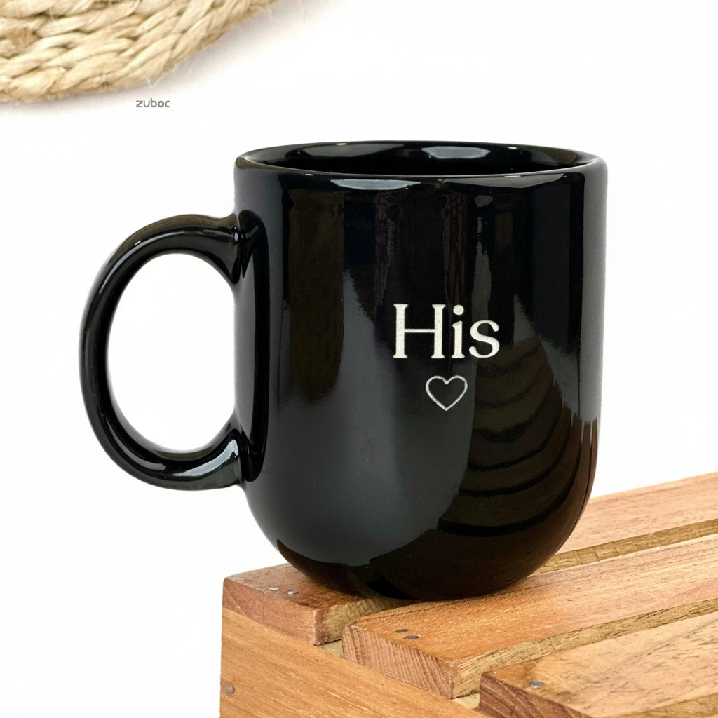 Two black mugs stacked on top of each other, one with 'His' and the other with 'Her', on a white background.