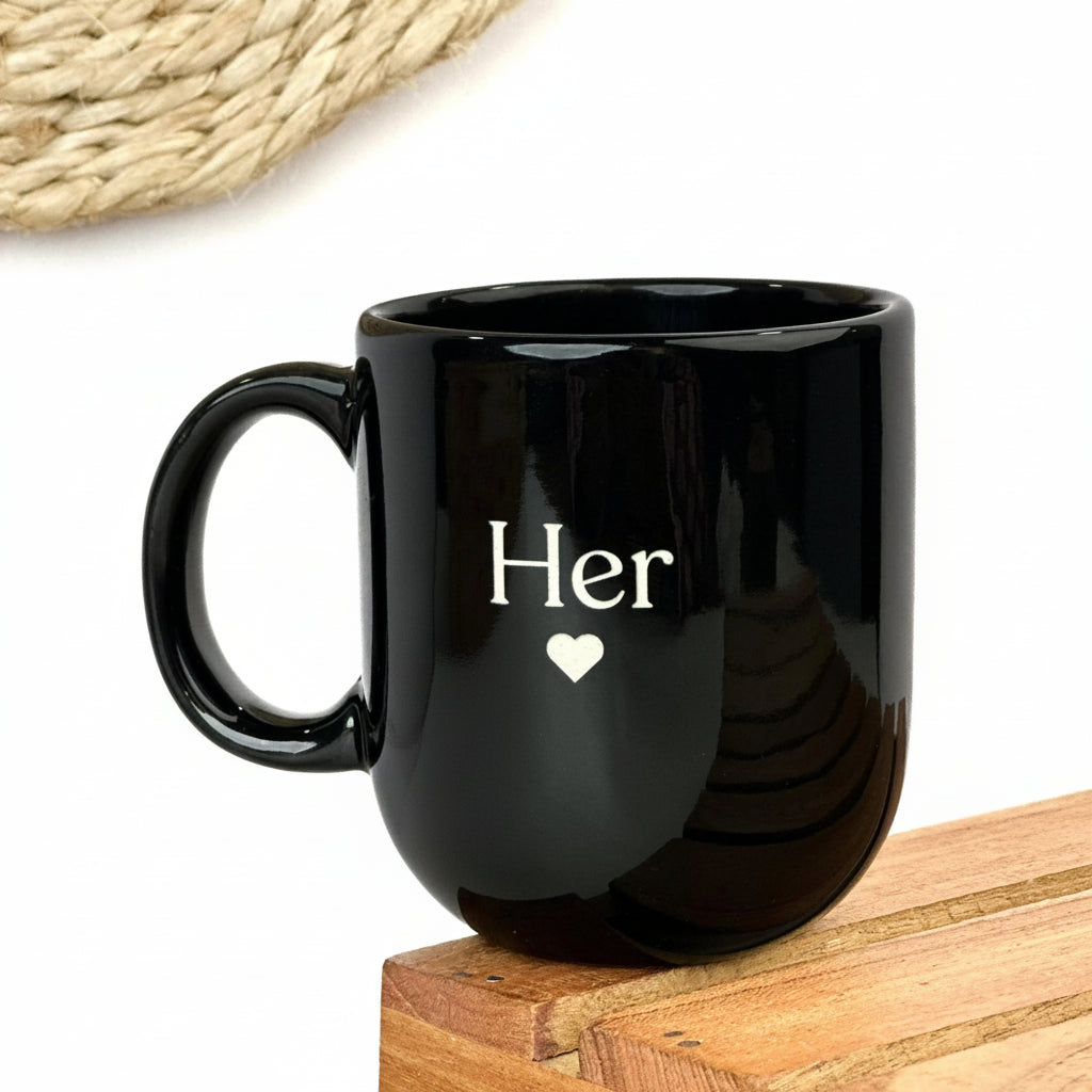 Two black mugs stacked on top of each other, one with 'His' and the other with 'Her', on a white background.