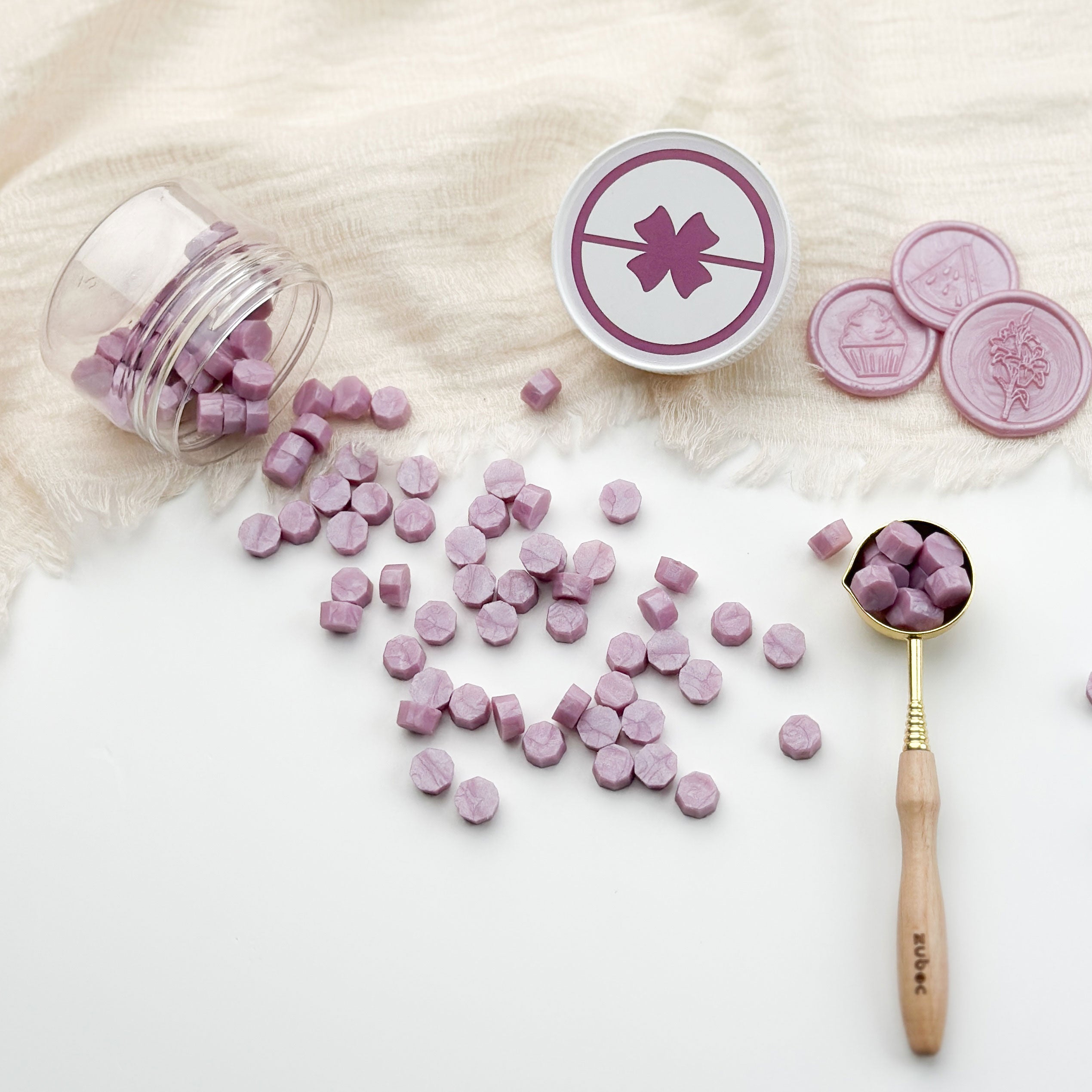 Purple round candies with a container, spoon, and cookies on a light background