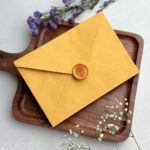 Mango yellow std envelope with light gold hydrangea wax seal