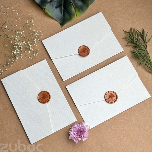 Light grey invitation envelope paired with a bronze gold wax seal.