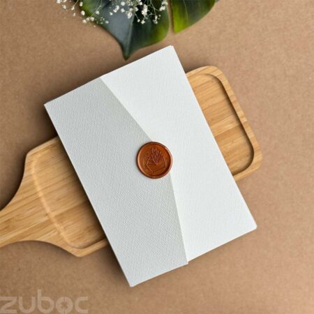 Light grey invitation envelope paired with a bronze gold wax seal.